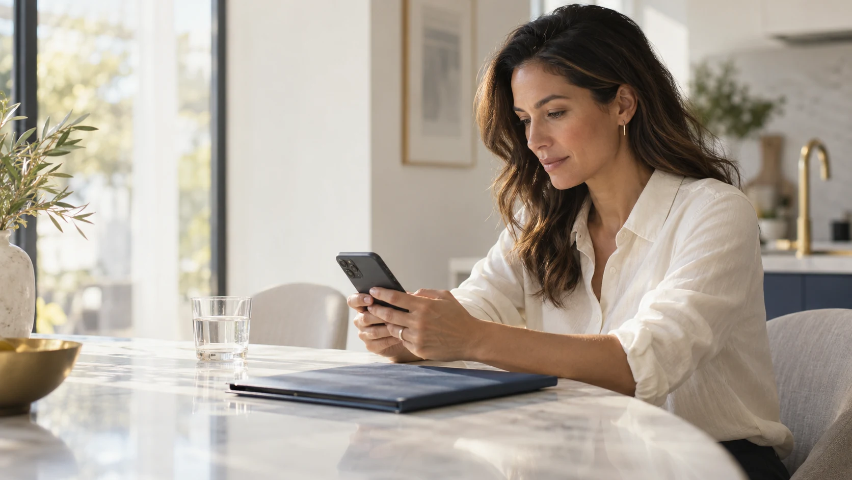 A borrower reviewing a smartphone at a sunlit kitchen table